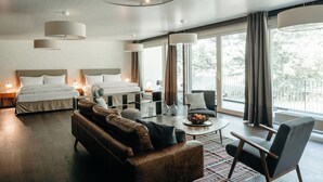 A modern hotel room with a large bed, a sofa, a coffee table, and a balcony with curtains. - Schloss Huenigen (Konolfingen)