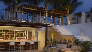 A modern outdoor lounge area with a bar, seating, and a staircase leading to an upper level. - Grand Beach Hotel Surfside (Surfside)