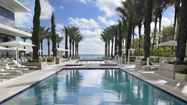 A poolside area with lounge chairs, a pool, and a view of the ocean. - Grand Beach Hotel Surfside (Surfside)