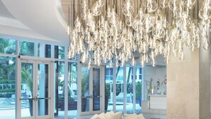 A modern interior with a white sofa, a wooden coffee table, and a hanging light fixture. - Grand Beach Hotel Surfside (Surfside)