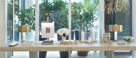 Un intérieur moderne avec une table à plateau en verre, des objets décoratifs et une vue sur la verdure à l’extérieur.