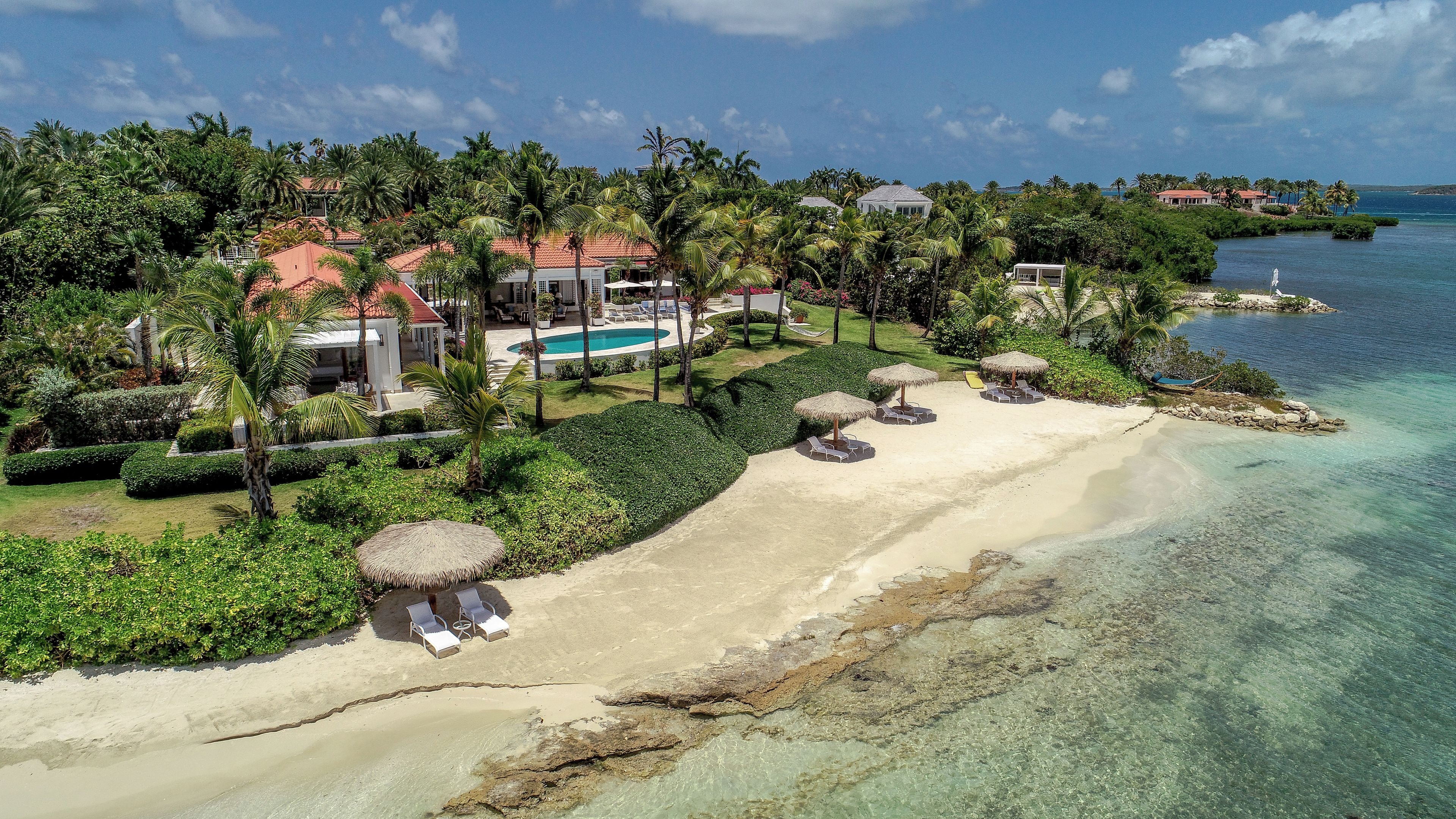 A tropical resort with a swimming pool, beach area, and lush greenery.