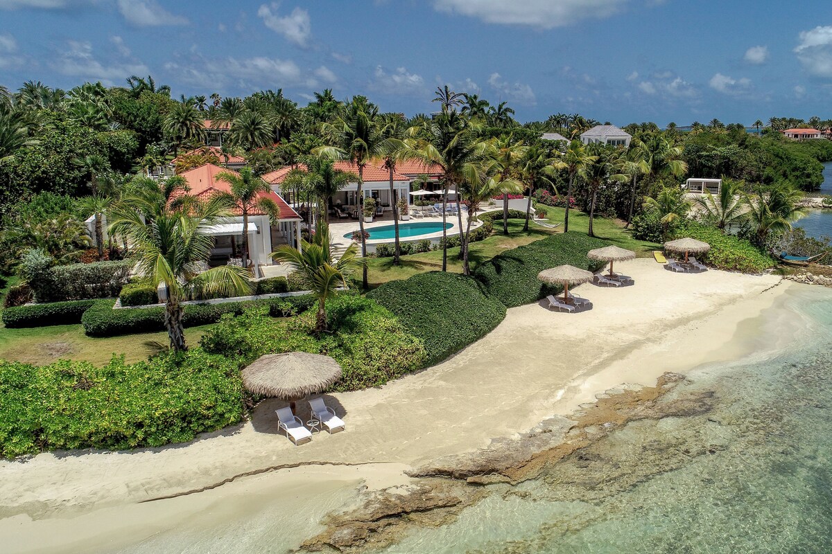 A tropical resort with a swimming pool, beach area, and lush greenery.