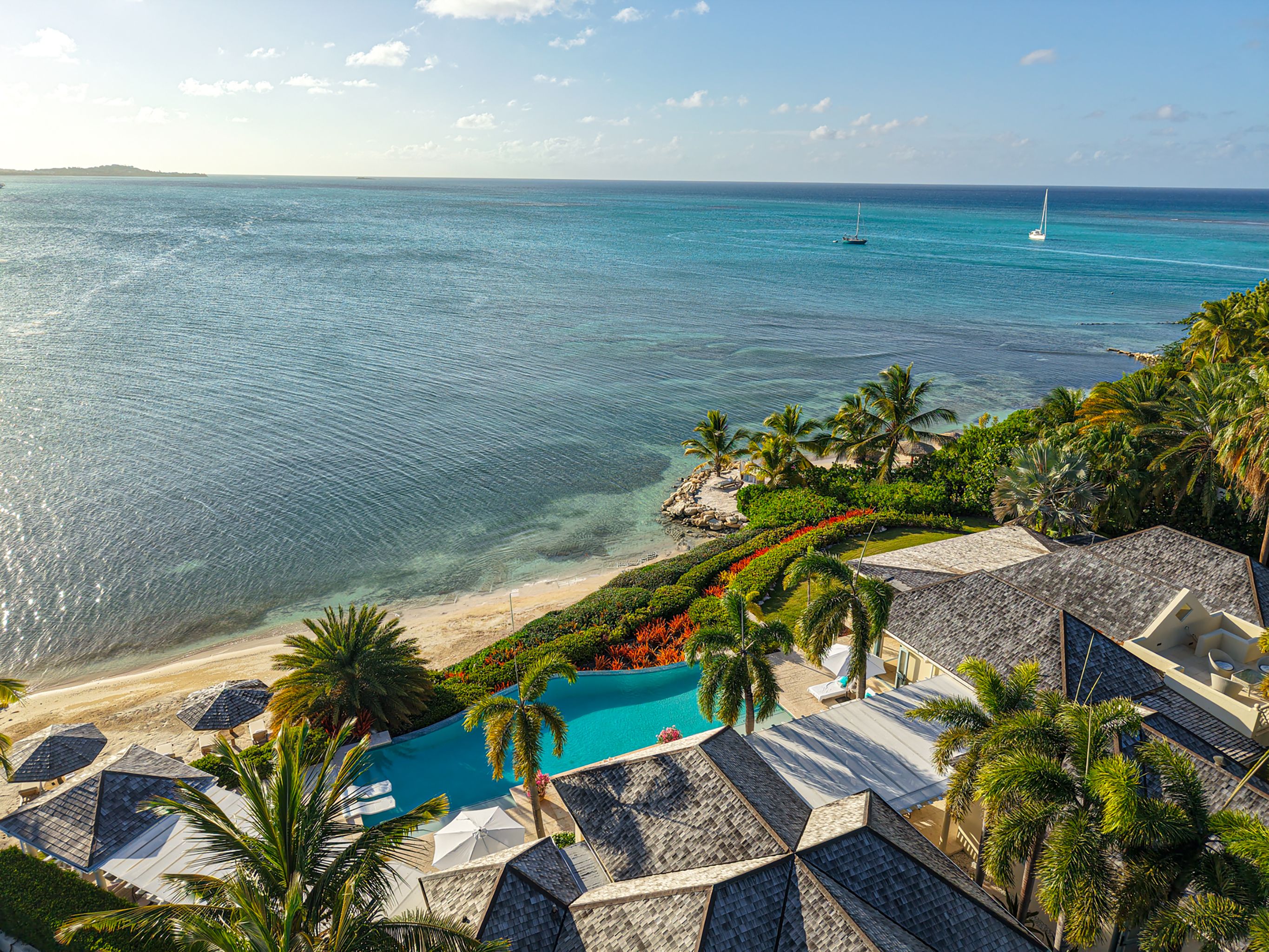 A resort with a swimming pool, beach, and ocean view.