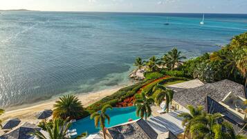 A resort with a swimming pool, beach, and ocean view.