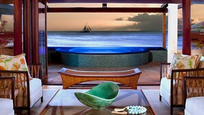 Elegante zona de estar al aire libre con vista al océano y un velero.