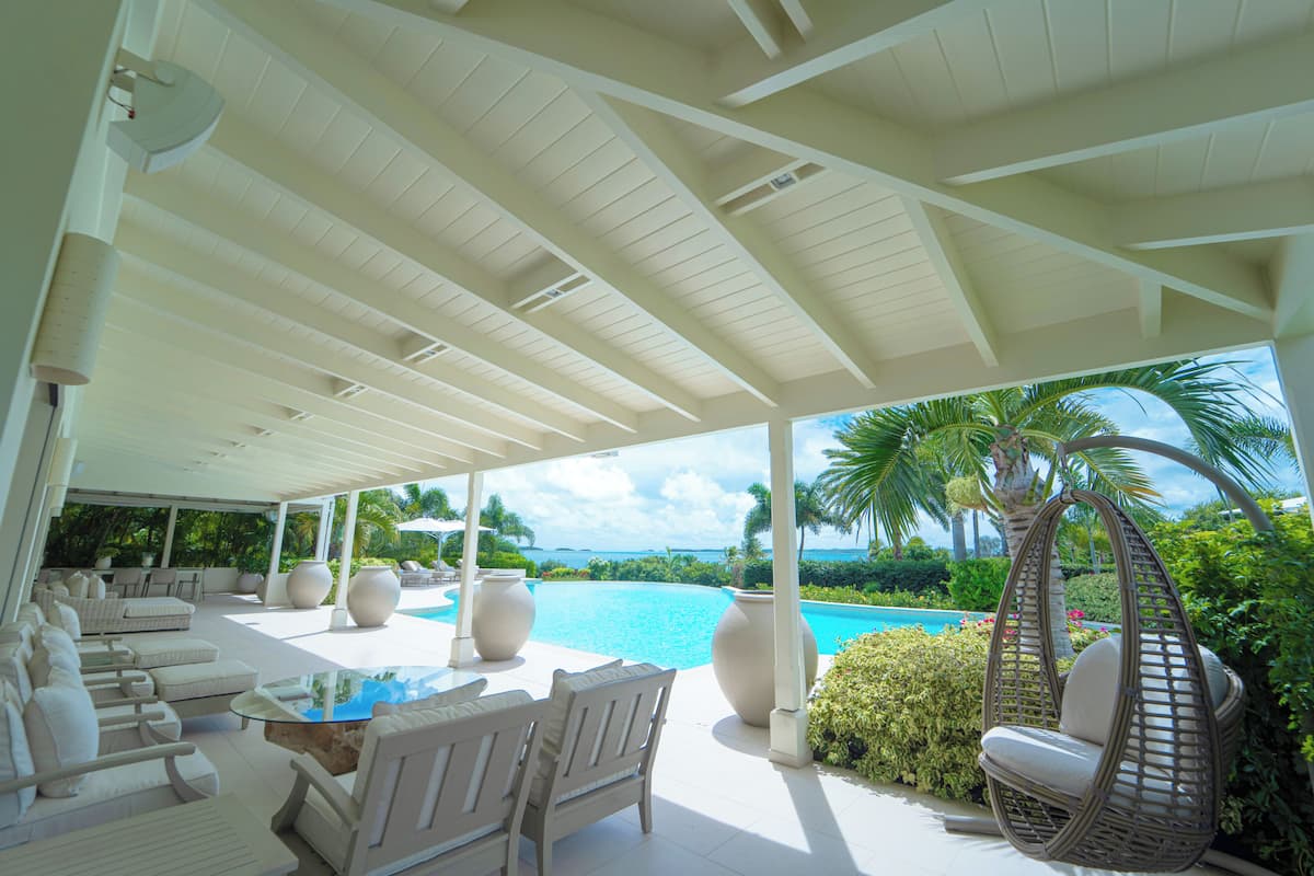 A covered outdoor area with seating, a pool, and a view of the ocean.