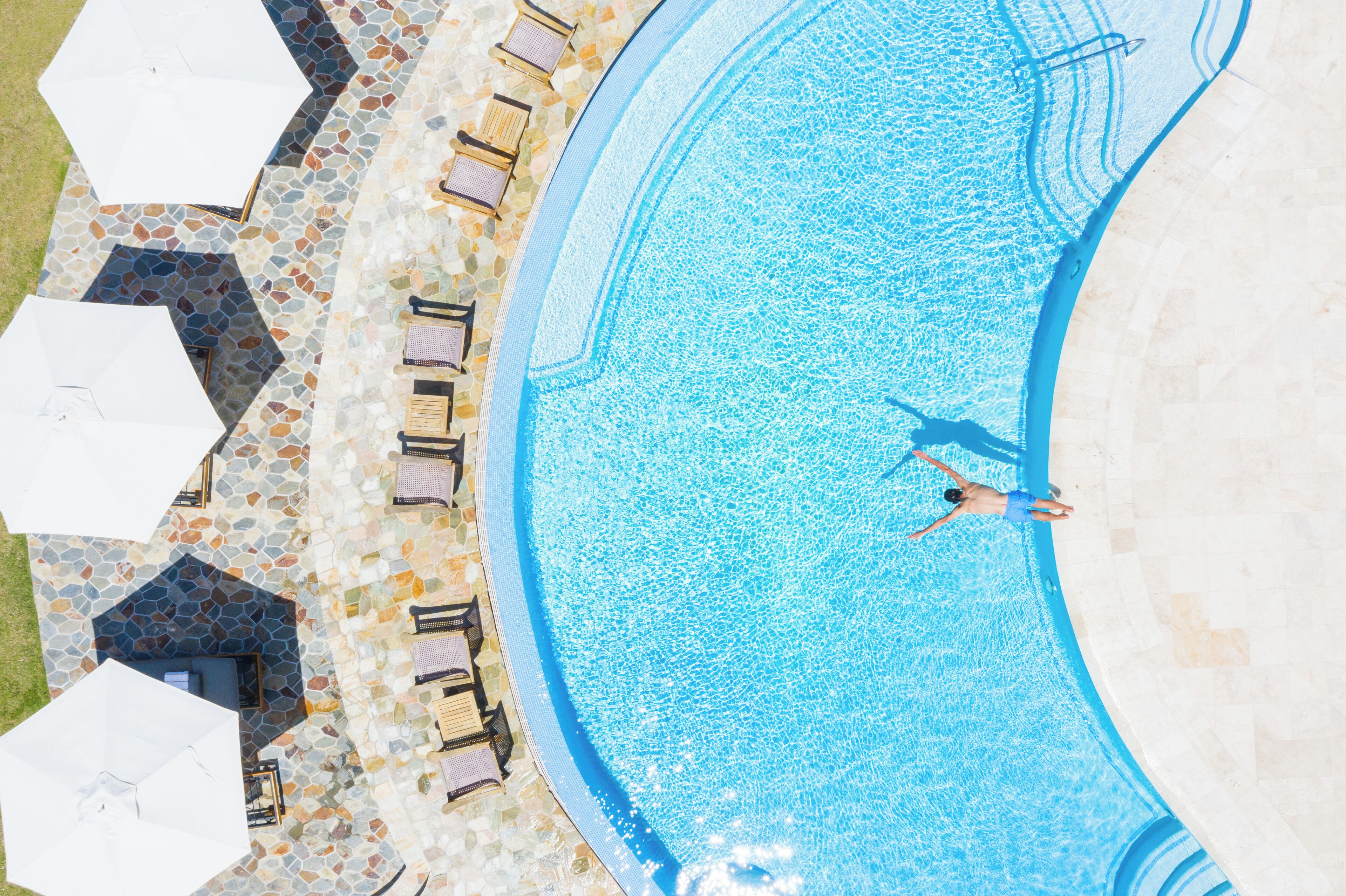 Vista aérea de una piscina con sillas de descanso y sombrillas.