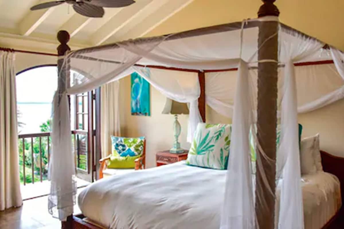 A four-poster canopy bed with a view of the outdoors.