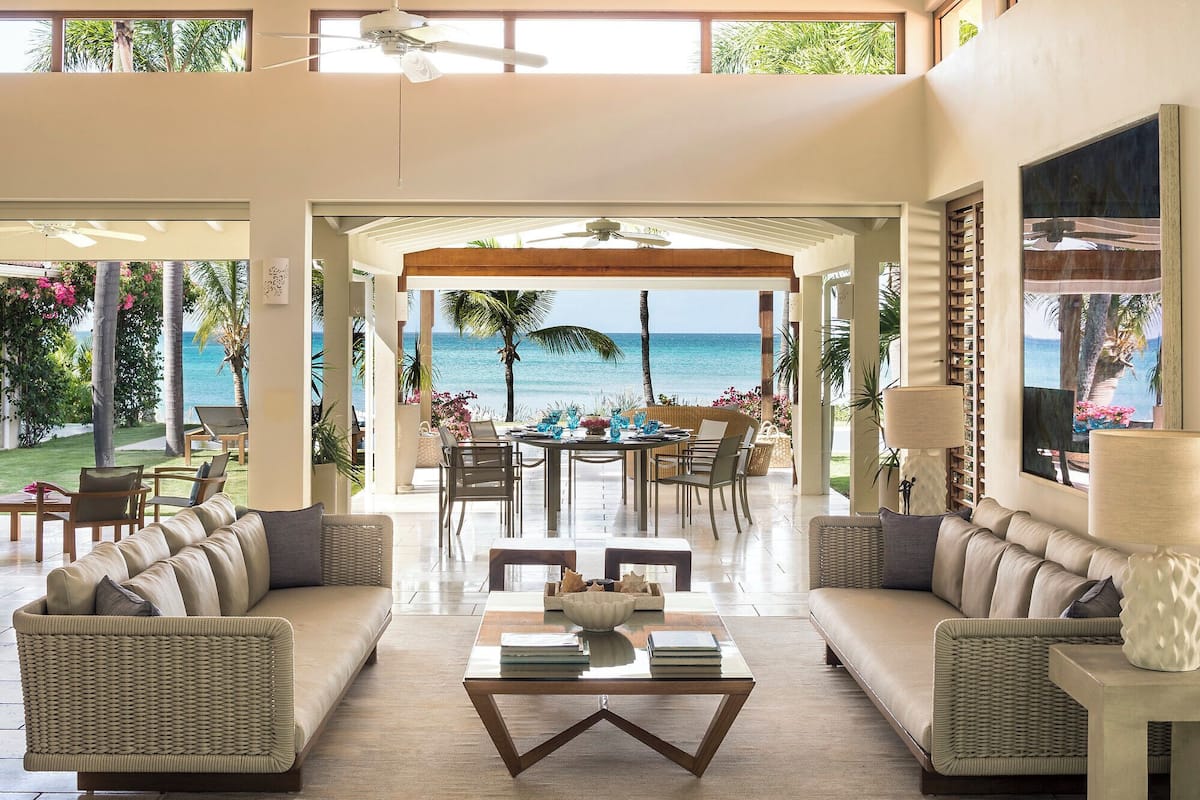 A spacious living area with a view of the ocean, a dining table with chairs, and comfortable seating.