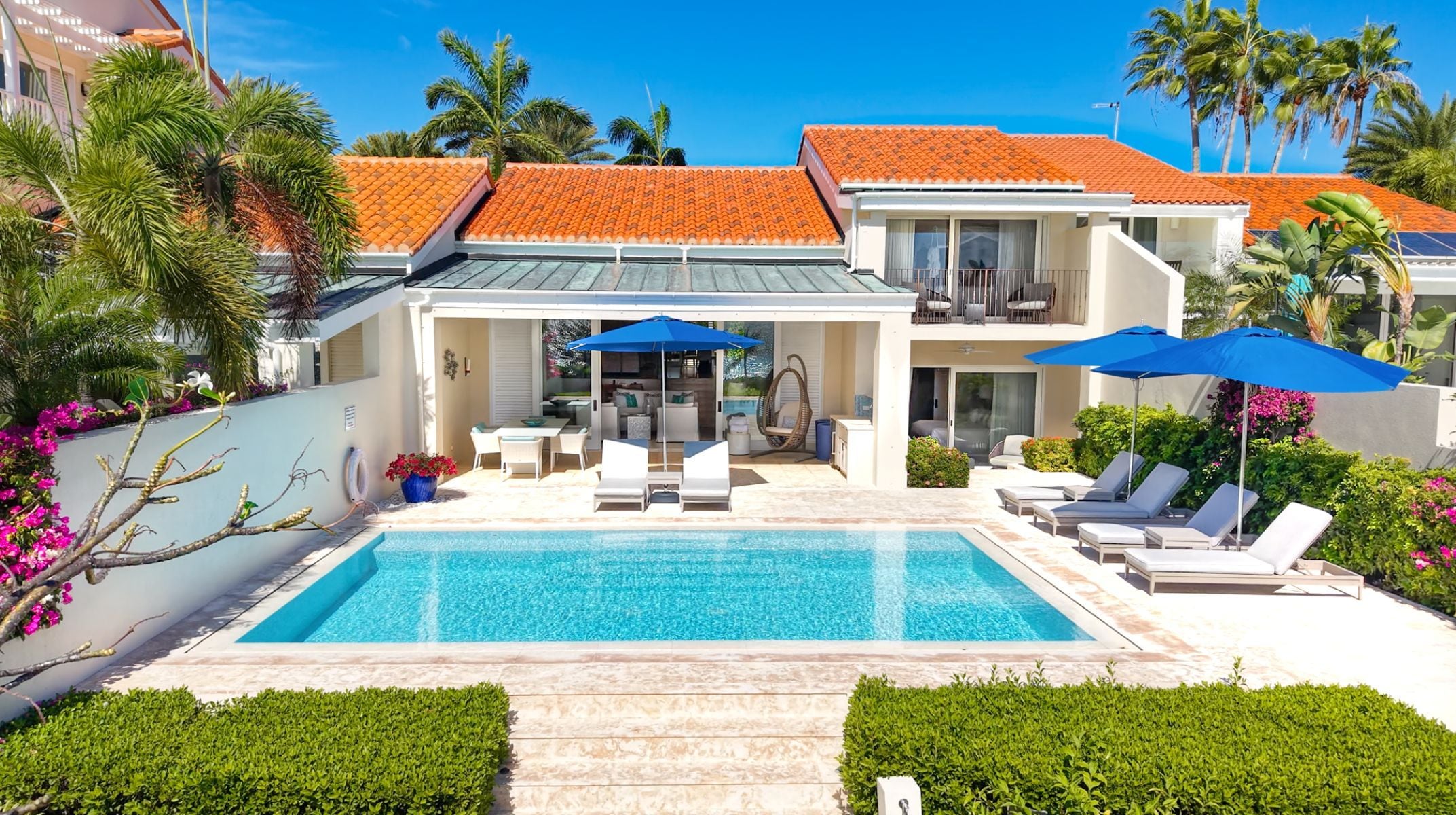 Una moderna casa con piscina, area salotto esterna e patio coperto.