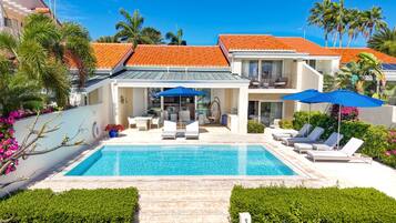 Una moderna casa con piscina, area salotto esterna e patio coperto.