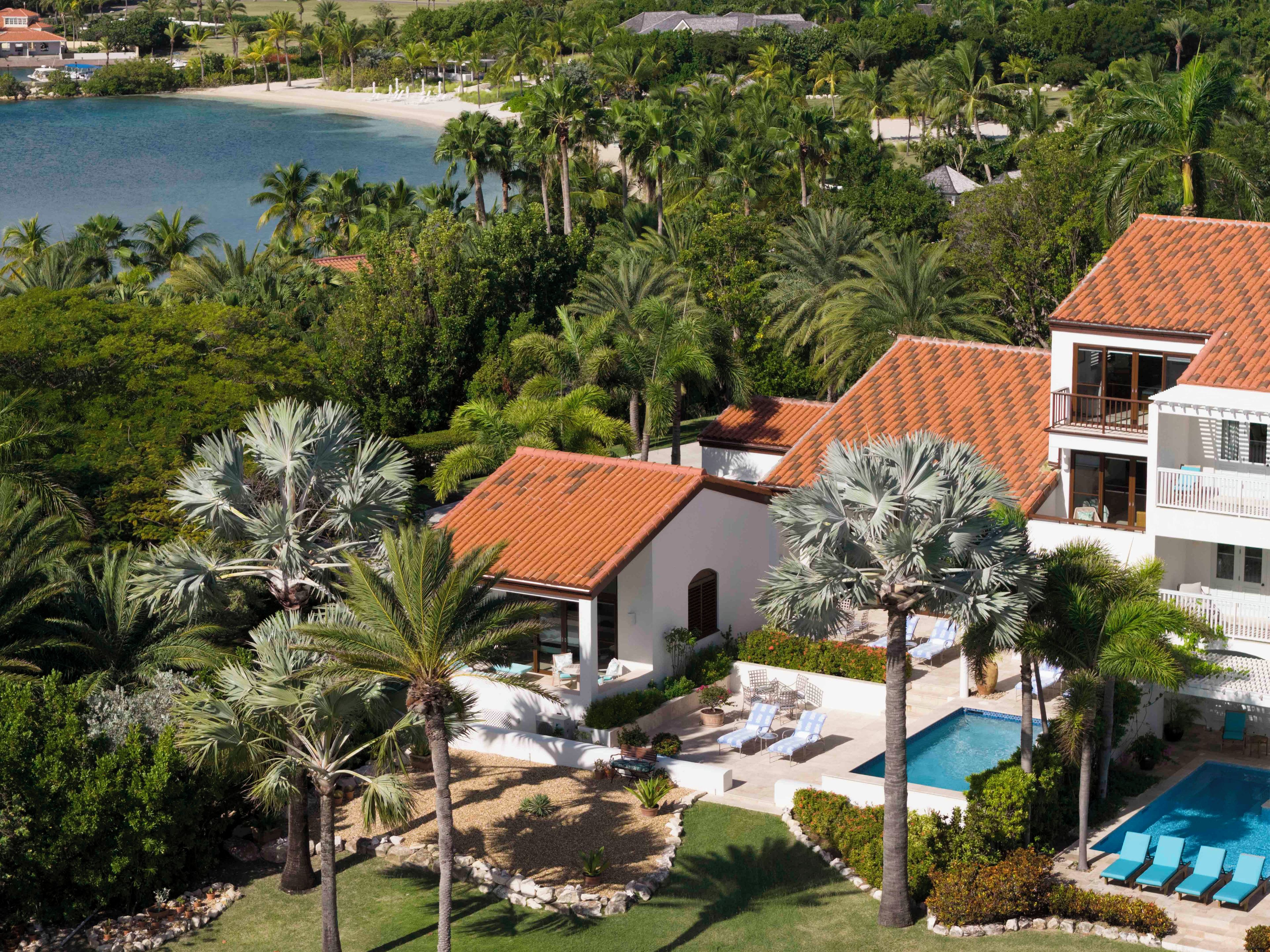 A residential area with a swimming pool, palm trees, and a beach.