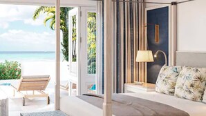 Un dormitorio con cama, mesita de noche, lámpara y vistas a la playa.