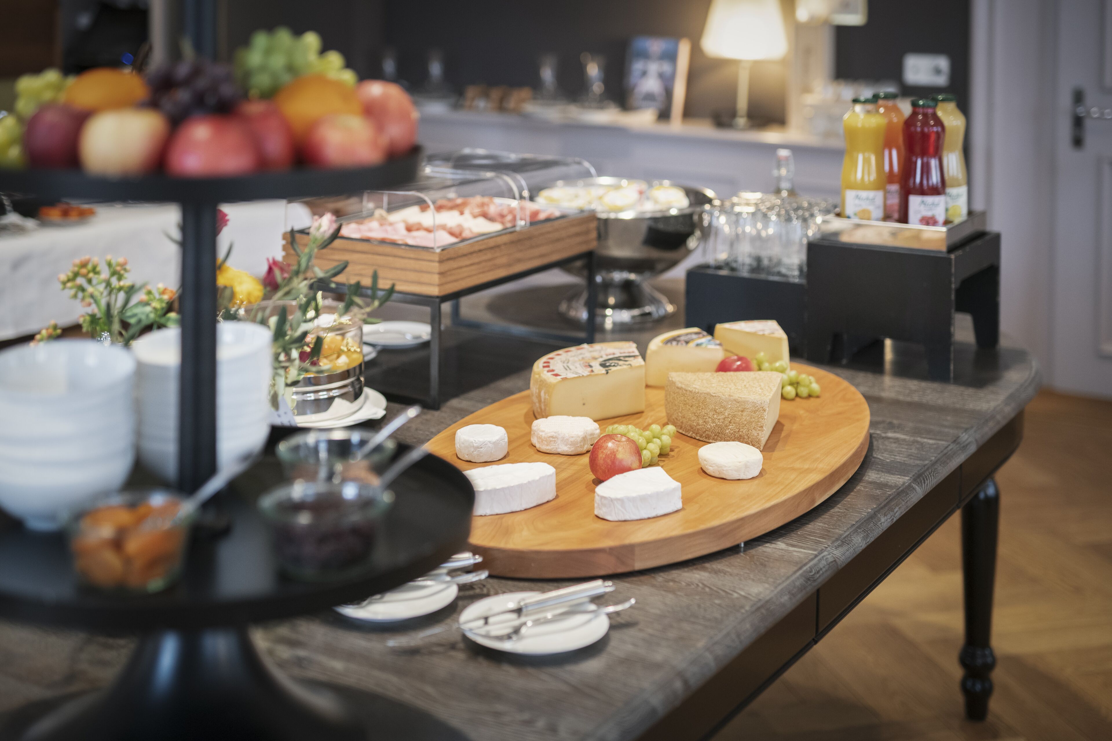 A buffet table with various cheeses, fruits, and condiments.