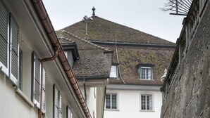 En smal brostensgade omkranset af historiske bygninger med buede vinduer og et skilt med teksten 