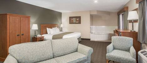 A hotel room with a sofa, armchair, bed, bedside table, lamp, and a small table with a basket.