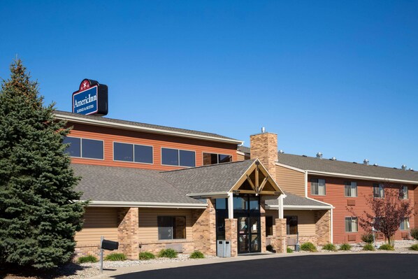 A hotel with a prominent American Inn sign, brick facade, and a covered entrance.
