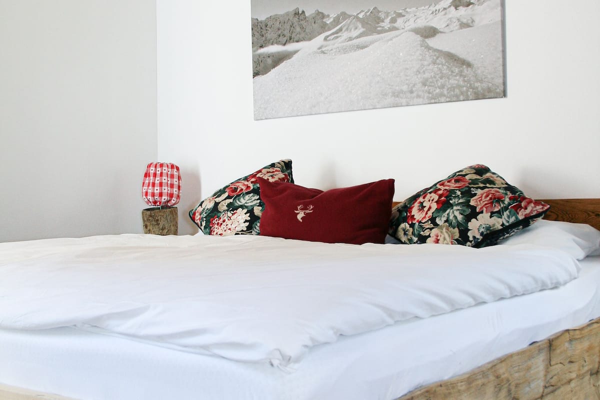 A bed with white linens, a wooden headboard, and floral pillows.