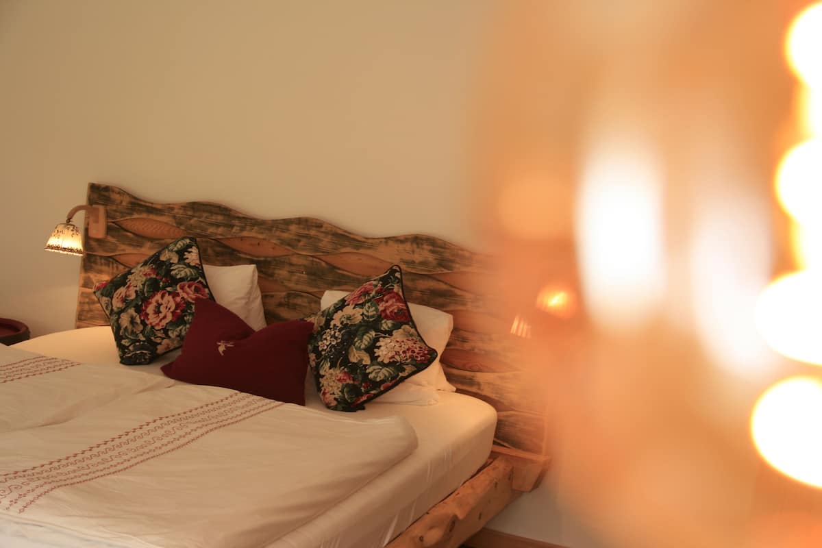 A bed with a wooden headboard, white bedding, and floral-patterned pillows.