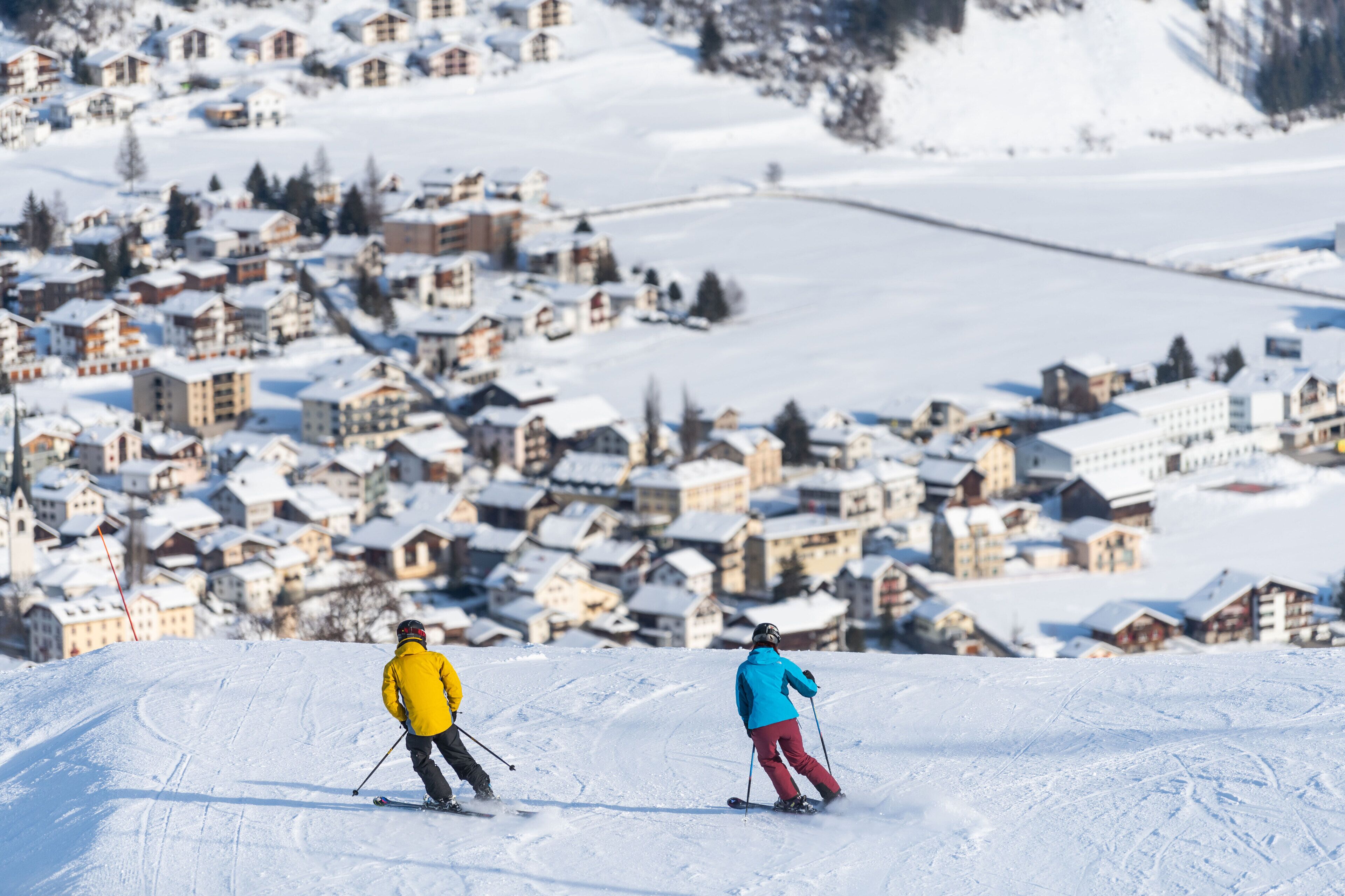 A snowy village with traditional houses and a ski slope.