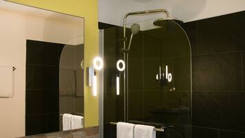 A modern bathroom with a glass-enclosed shower, a visible towel rack, and a mirror with lights.
