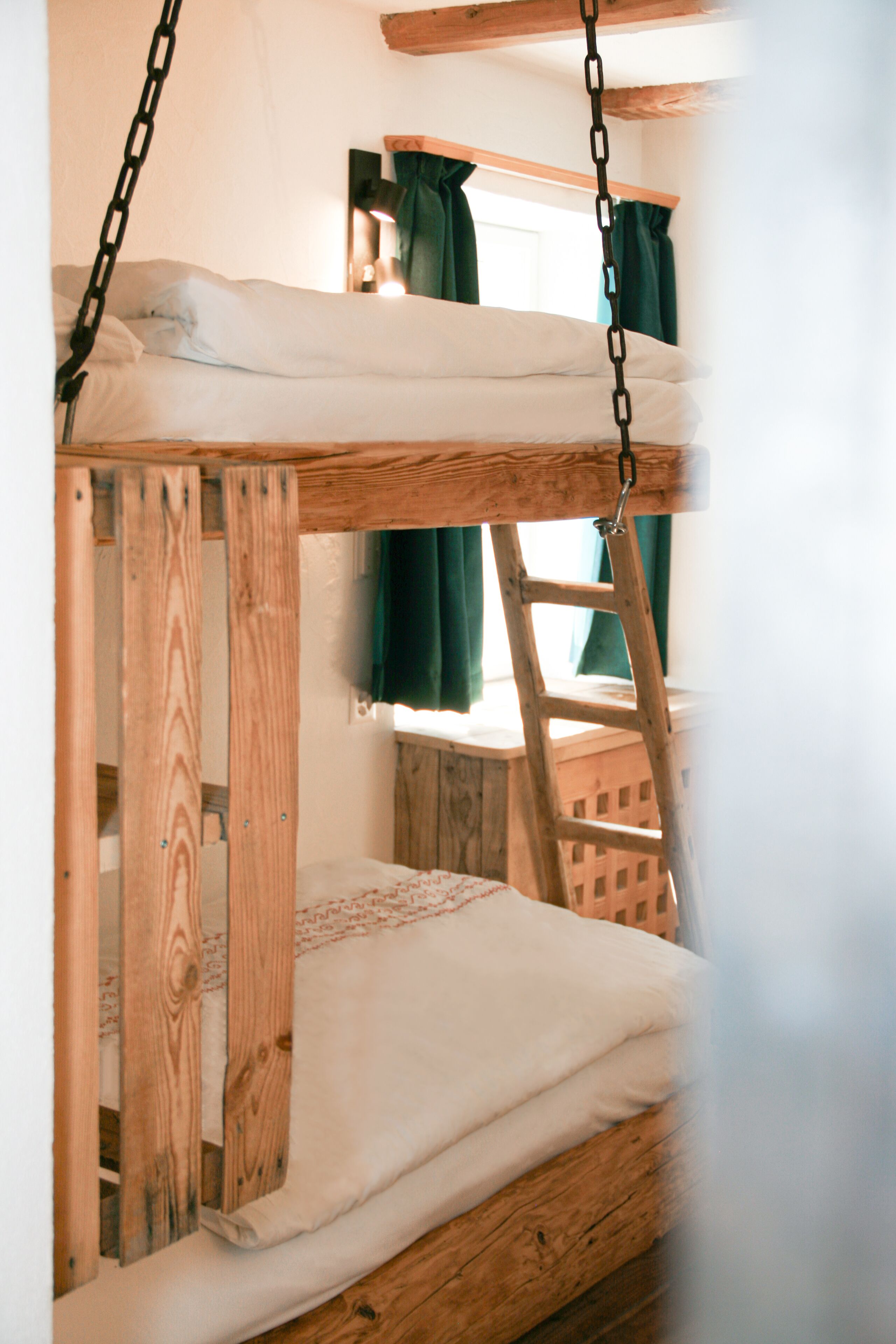 A bunk bed with wooden frames and white bedding.