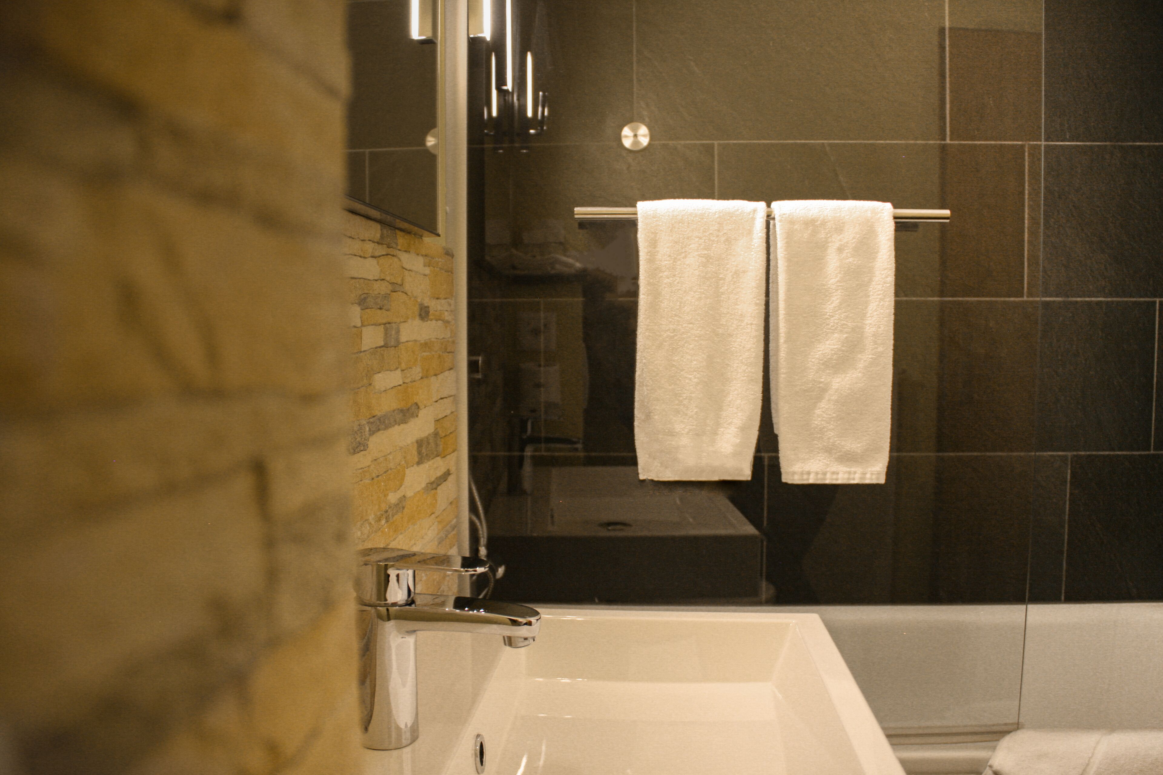 Ein Badezimmer mit Badewanne, Duschkabine und einem Handtuchhalter mit zwei weißen Handtüchern.