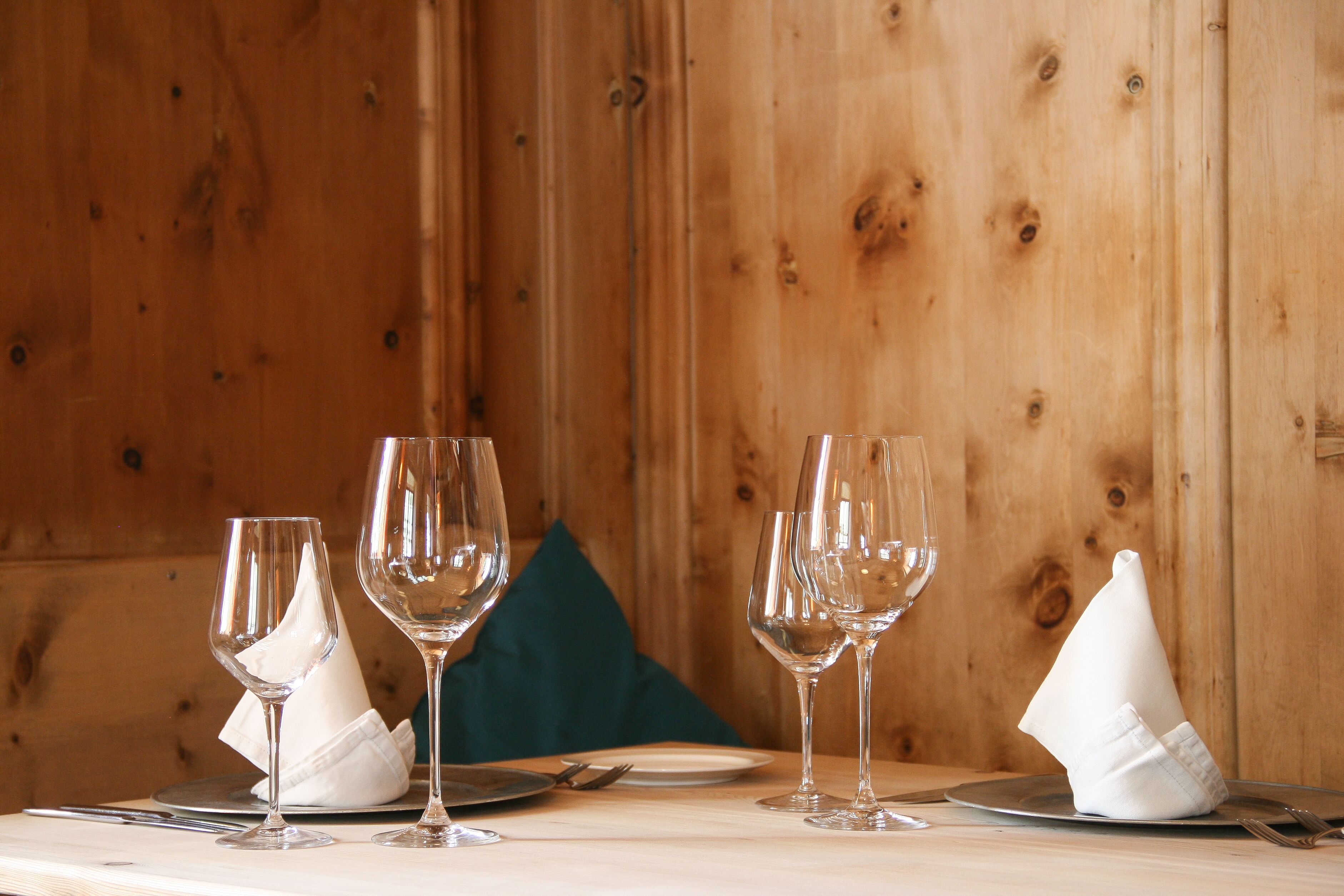A wooden interior with a table set for dining, featuring clear glassware and white napkins.