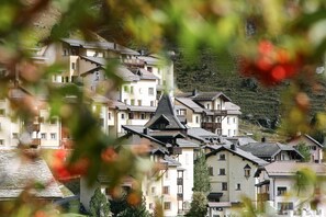 A cluster of multi-story buildings with balconies, set against a hillside backdrop. - Hotel Solaria (Surses)