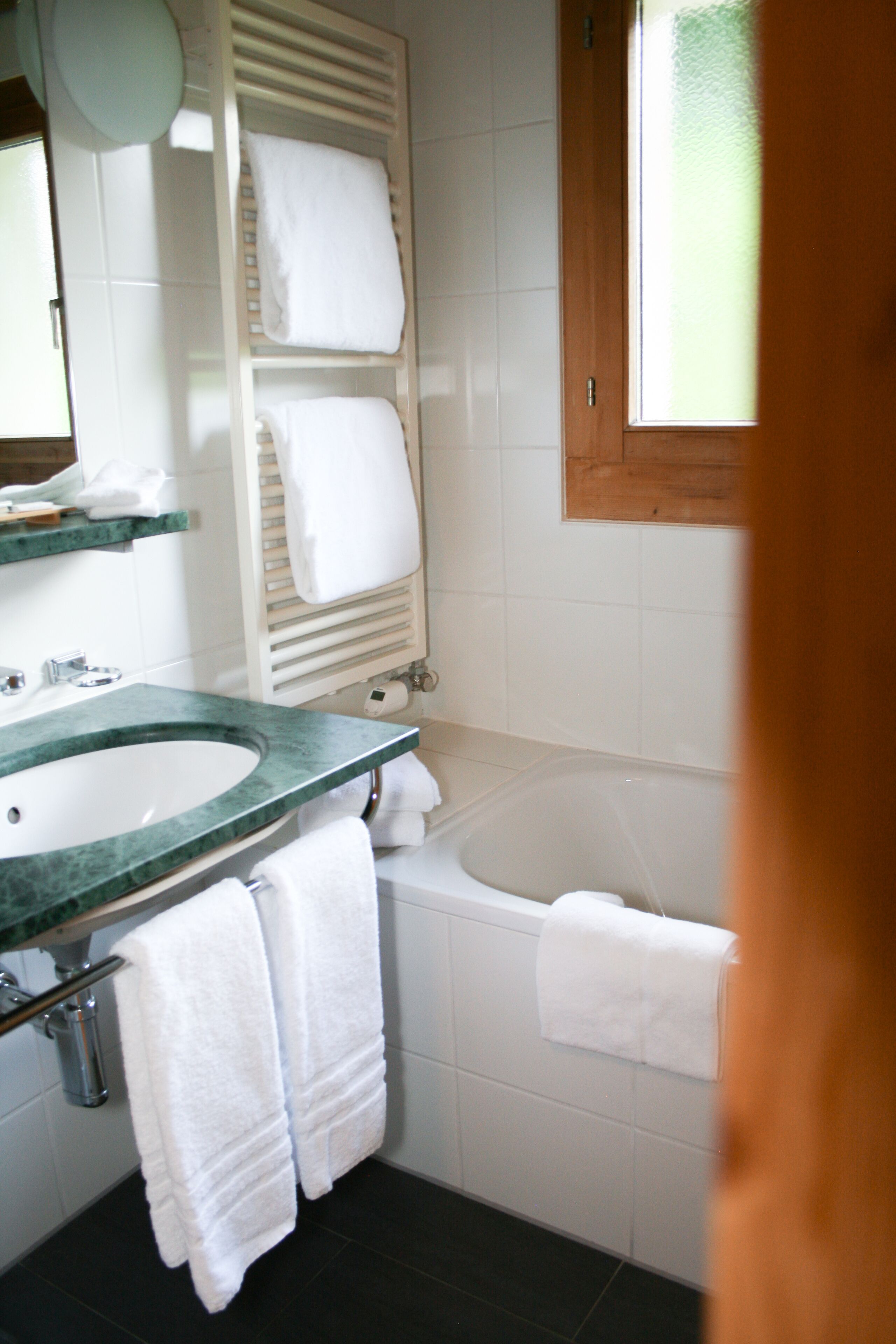 A bathroom with a sink, mirror, towel rack, and bathtub.
