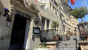 Un edificio con una entrada imponente, varias banderas suizas y una escalera que conduce a la entrada.