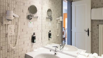 Ein Badezimmer mit einem Doppelwaschbecken, zwei Spiegeln, einem Fön und einem Handtuchhalter.