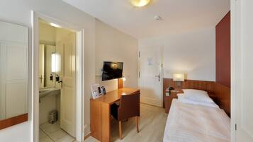 Une chambre d’hôtel avec un bureau en bois, une télévision, un lit et une petite salle de bain.