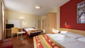 A hotel room with two beds, a desk, a chair, a TV, and a painting on the wall.