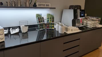 Ein Café mit einer Kaffeemaschine, einer Kaffeemühle und einer Auswahl an Kaffeekapseln.