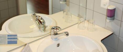 A bathroom with two sinks, a mirror, and a hairdryer mounted on the wall.