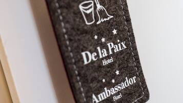 Primer plano de un tejido texturizado con bordado que dice 'De la Paix Hotel' y 'Ambassador Hotel'.