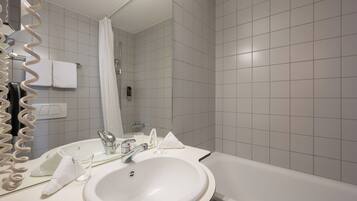A modern bathroom with a white sink, mirror, and shower.