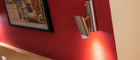 A metallic light fixture mounted on a red wall.