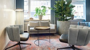 A modern living room with a sofa, two armchairs, a coffee table, and large potted plants. - TOP VCH Hotel Wartburg Stuttgart (Stuttgart)