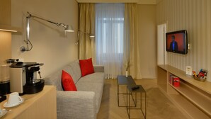 A modern living room with a sofa, a coffee machine, a TV, and a small table.