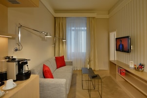 Una sala de estar moderna con un sofá, una cafetera, un televisor y una pequeña mesa.