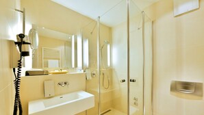 A modern bathroom with a glass-enclosed shower, a white sink, and a mirror above the sink.