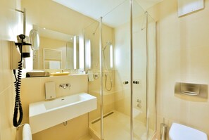 A modern bathroom with a glass-enclosed shower, a white sink, and a mirror above the sink.