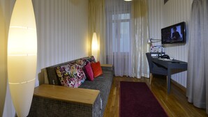 A living room with a sofa, a desk, a television, and a lamp.