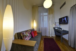 A living room with a sofa, a desk, a television, and a lamp.