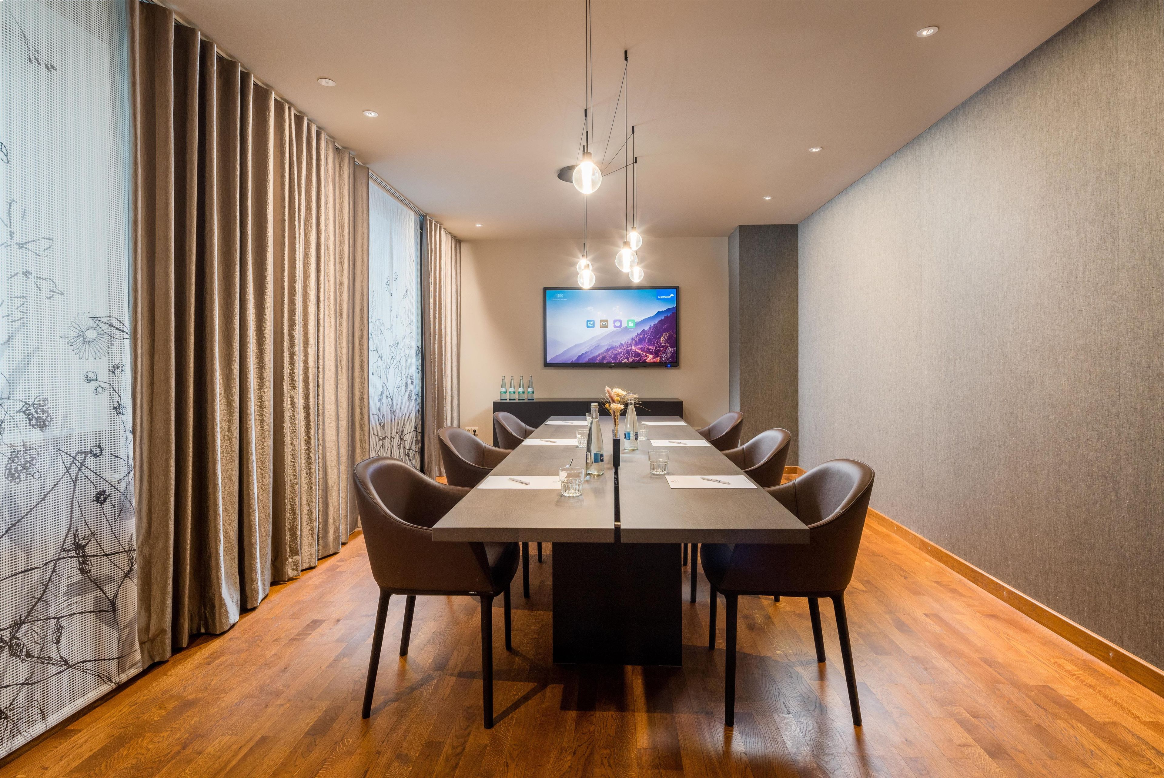 Una sala de conferencias con una larga mesa, sillas, un televisor de pantalla plana y una decoración de pared.