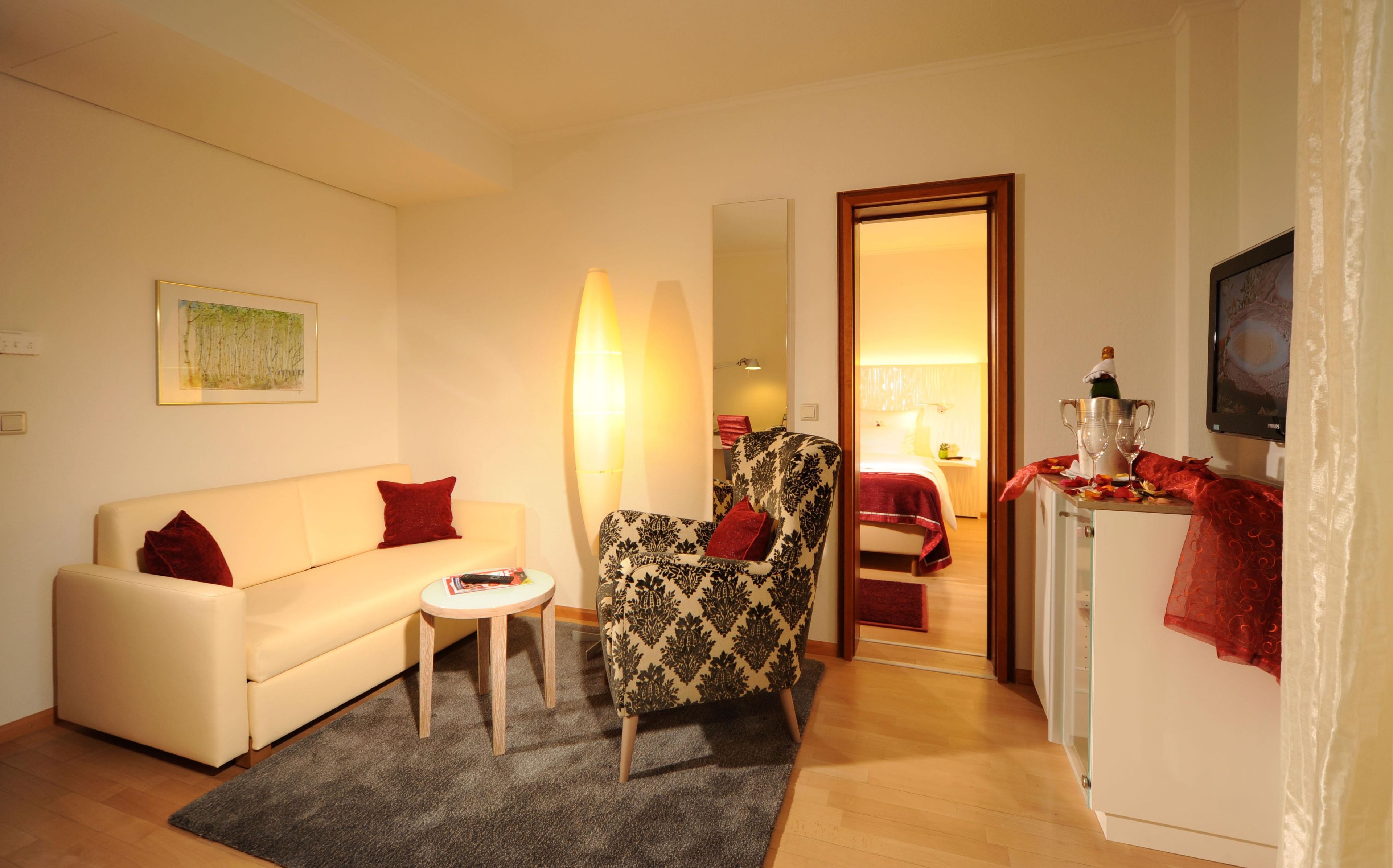 A living room with a sofa, armchair, small table, and a TV.