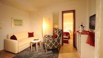 A living room with a sofa, armchair, small table, and a TV.